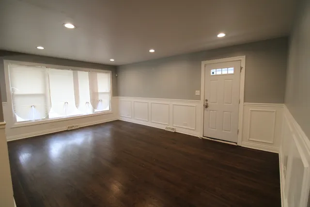 an empty room with wooden floor fan and window