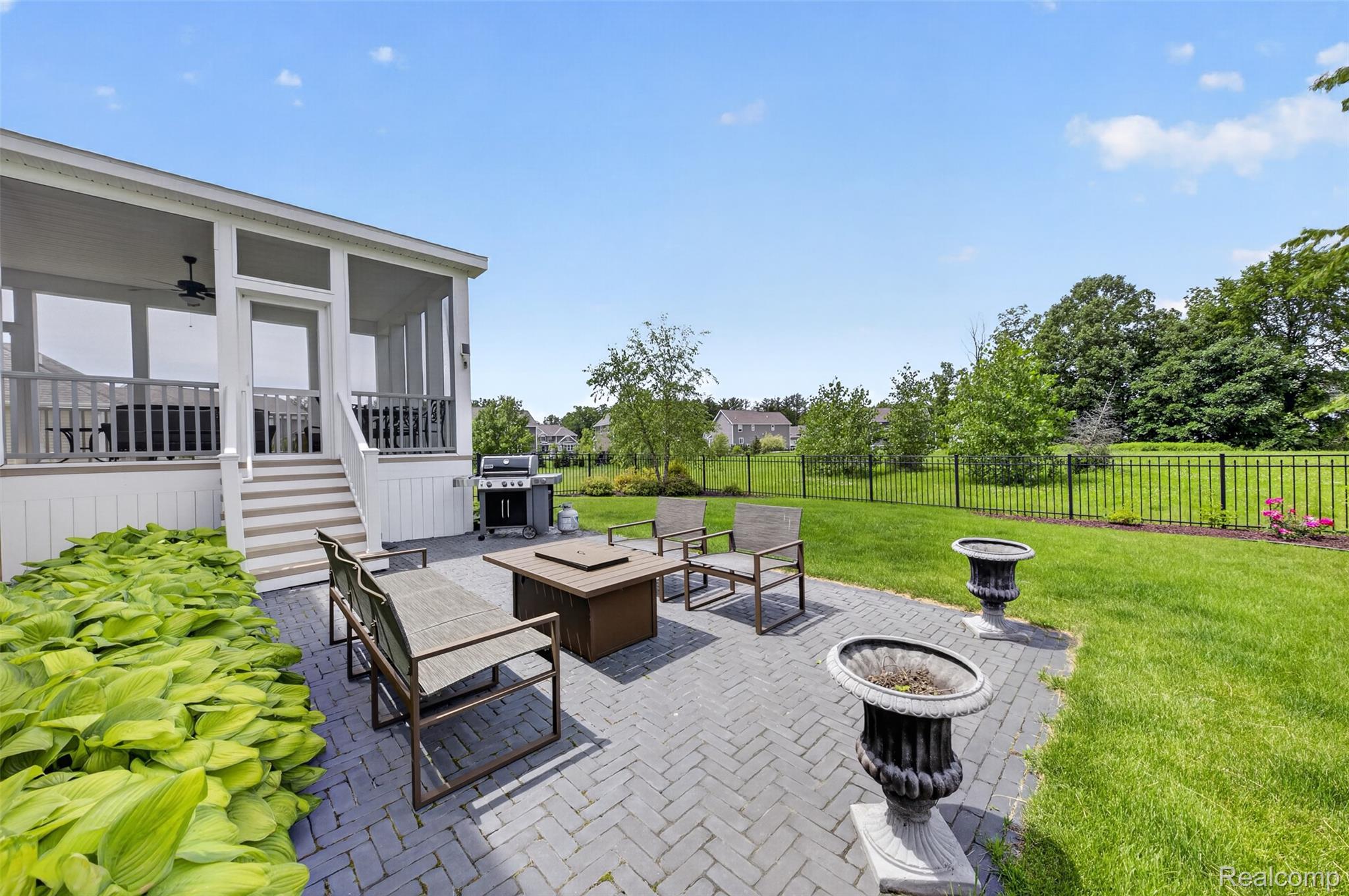 2531 Walnut View Drive Howell, MI 48855 - Photo 31 of 34 Expansive paver patio with a fire pit, bordered by a manicured lawn and mature landscaping
