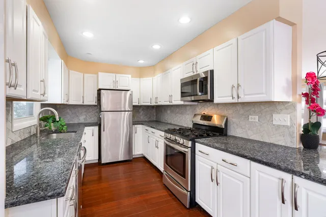 a kitchen with granite countertop a stove a sink a microwave a refrigerator and cabinets