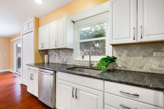 a kitchen with granite countertop a sink a stove and cabinets