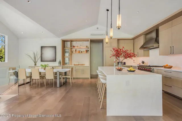 a dining room with wooden floor a chandelier a wooden table and chairs