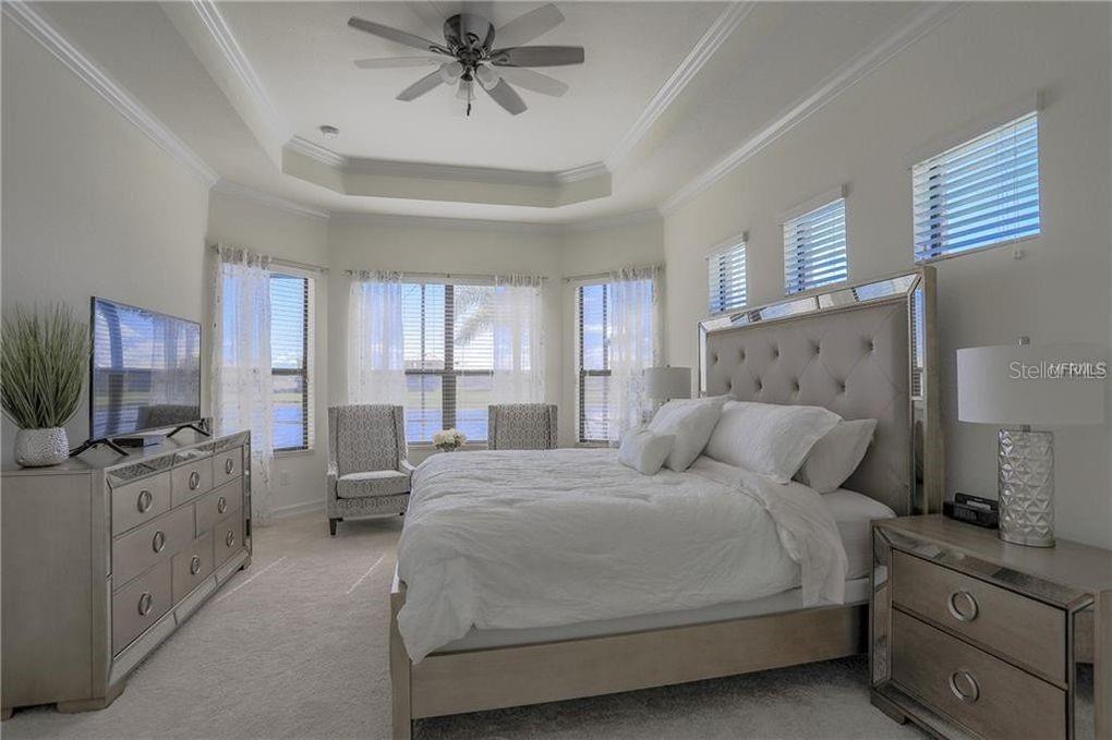 5528 Arnie Loop Lakewood Ranch, FL 34211 - Photo 18 of 59 a bedroom with a bed and a chandelier