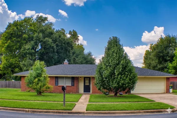a front view of a house with a yard and trees