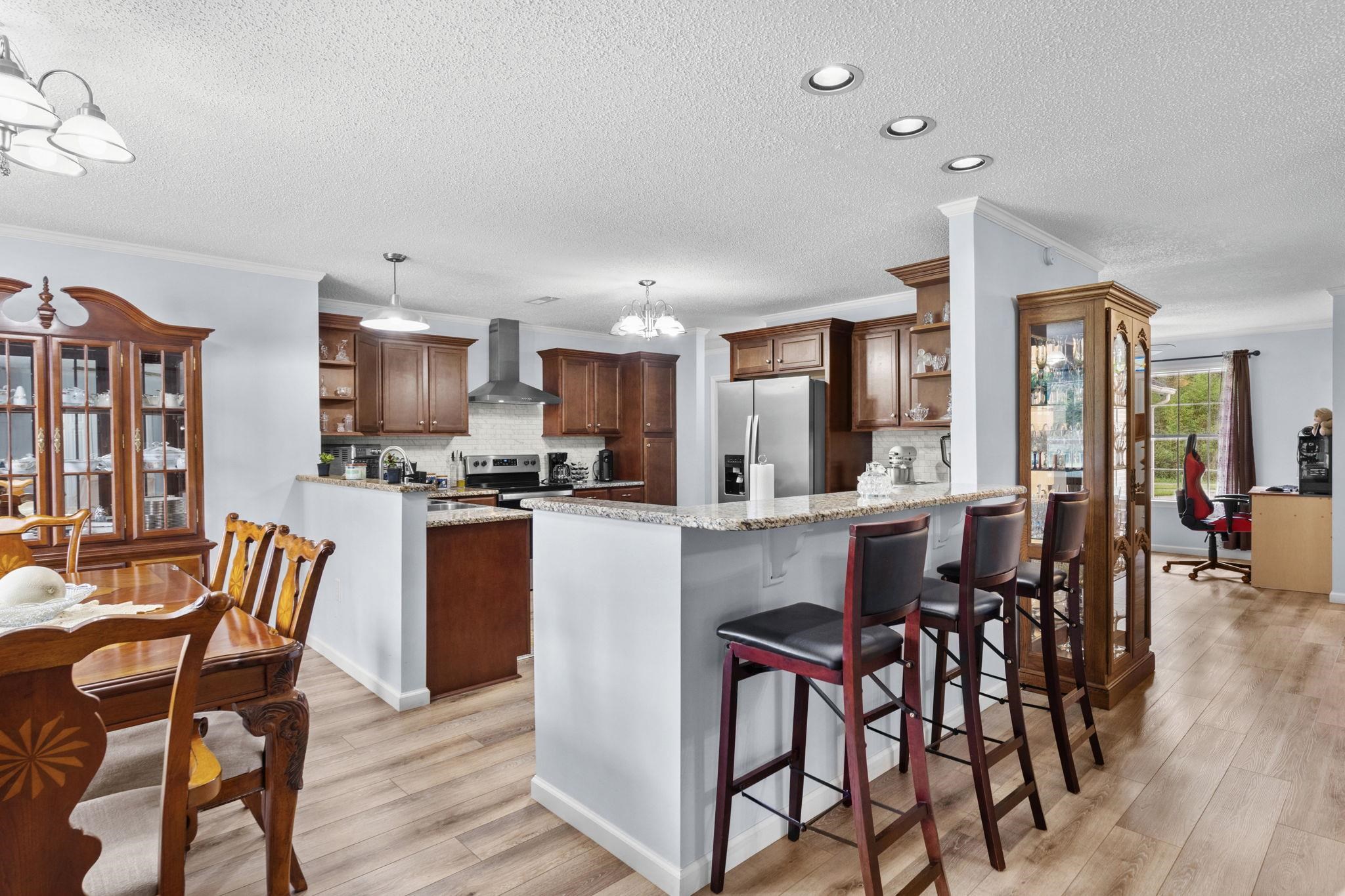 2981 Victor Road Longs, SC 29568 - Photo 12 of 32 Kitchen featuring open shelves, a chandelier, a peninsula, light stone countertops, and crown molding