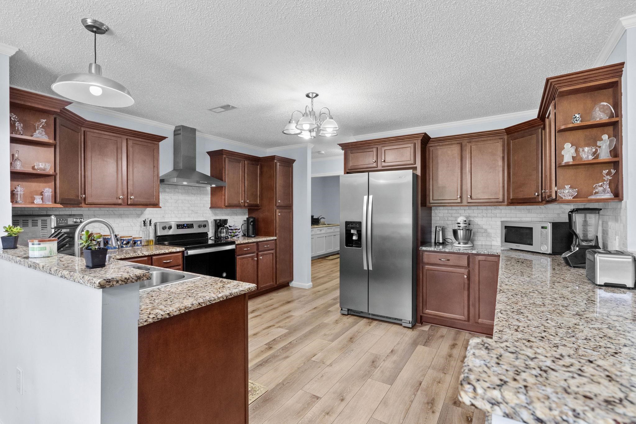 2981 Victor Road Longs, SC 29568 - Photo 13 of 32 Kitchen featuring open shelves, ornamental molding, light stone counters, light wood-style floors, and appliances with stainless steel finishes