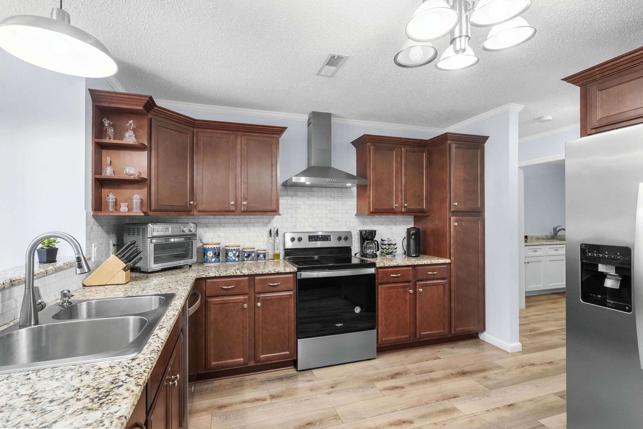 2981 Victor Road Longs, SC 29568 - Photo 14 of 32 Kitchen with appliances with stainless steel finishes, wall chimney exhaust hood, ornamental molding, light wood finished floors, and a textured ceiling