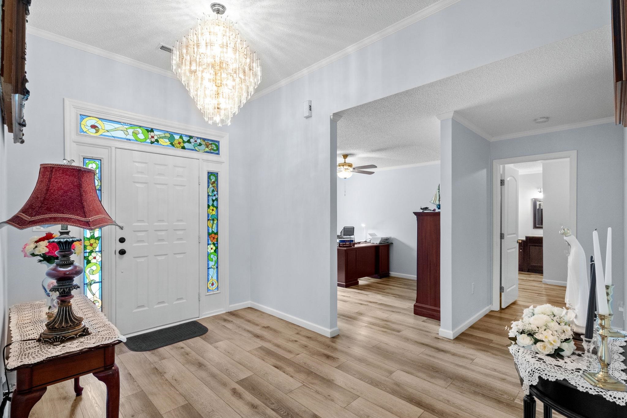 2981 Victor Road Longs, SC 29568 - Photo 6 of 32 Entryway with ornamental molding, a textured ceiling, a chandelier, a ceiling fan, and light wood-style flooring