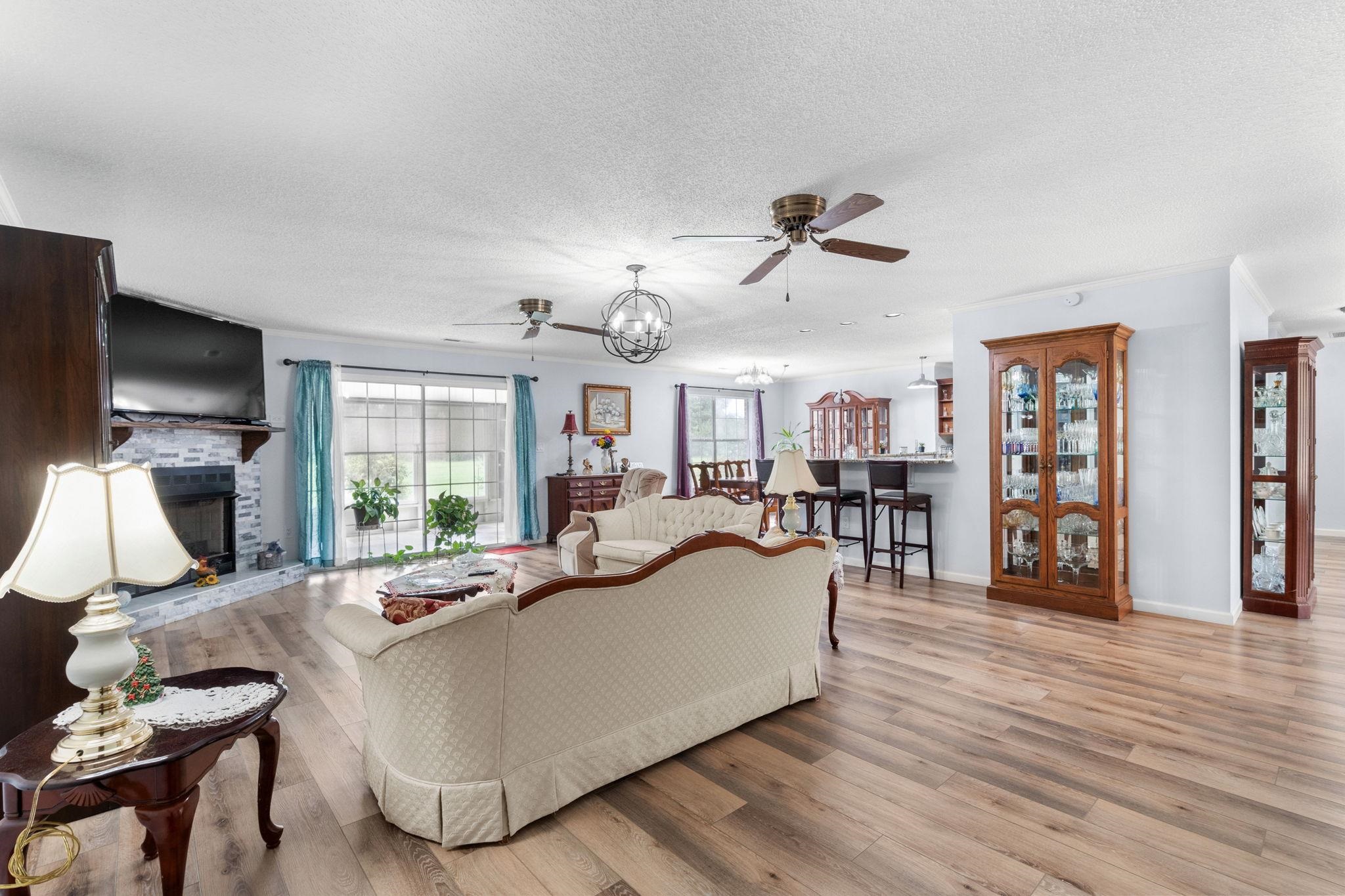2981 Victor Road Longs, SC 29568 - Photo 7 of 32 Living room featuring a ceiling fan, a chandelier, light wood-style floors, a textured ceiling, and a fireplace