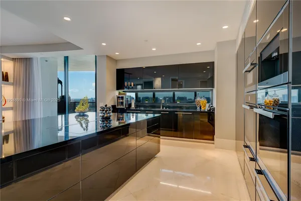 a living room with stainless steel appliances furniture a rug and a window