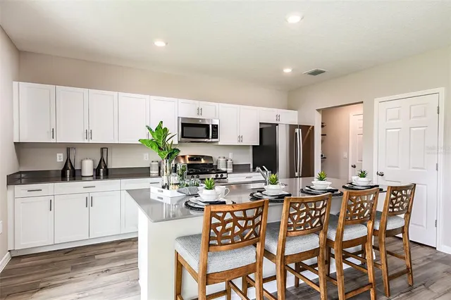 a kitchen with stainless steel appliances kitchen island granite countertop a sink a stove a dining table and chairs