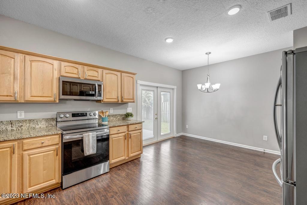 428 Sparrow Branch Circle St. Johns, FL 32259 - Photo 14 of 42 a kitchen with stainless steel appliances granite countertop a stove top oven a refrigerator and white cabinets with wooden floor