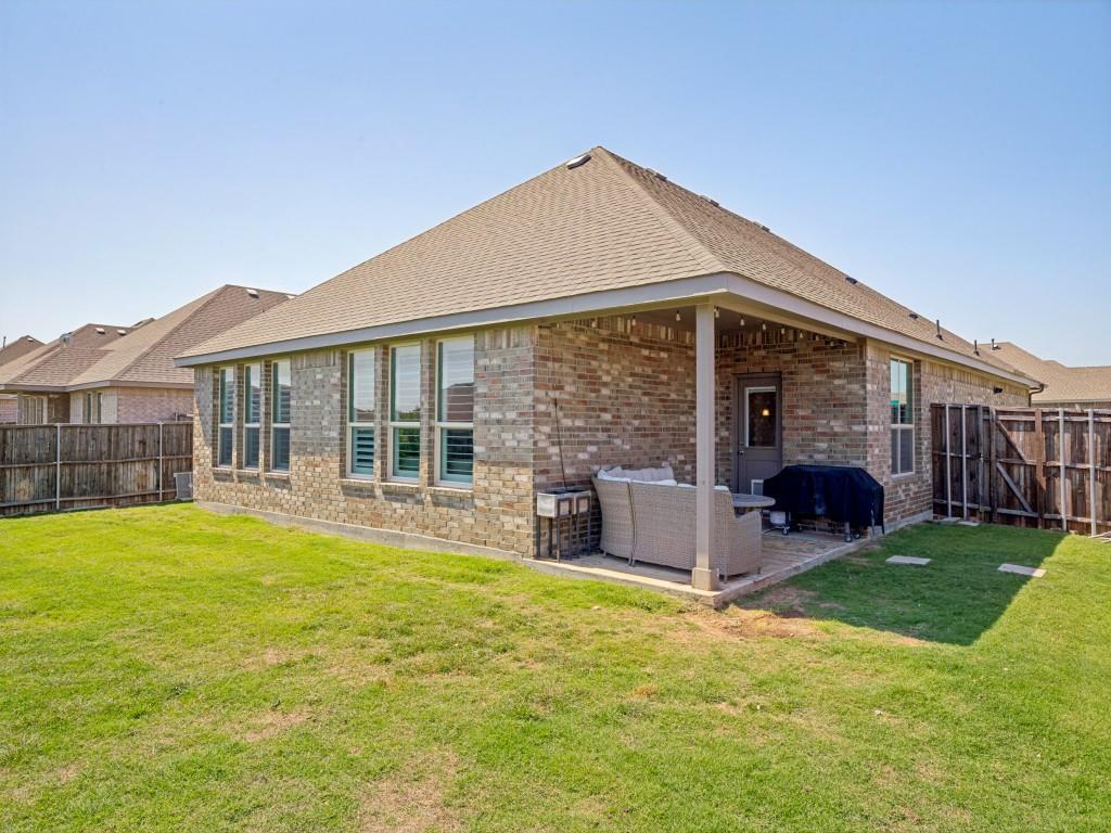 1612 Reed Drive Krum, TX 76249 - Photo 25 of 25 Rear exterior featuring a covered patio with brick paving, multiple windows with interior plantation shutters, and a shingled roof