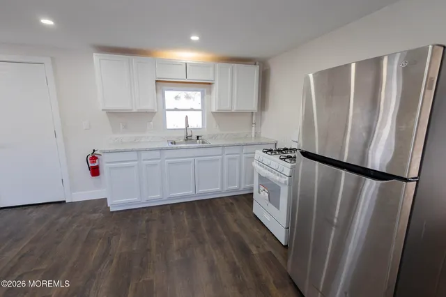 a kitchen with sink a refrigerator and white cabinets