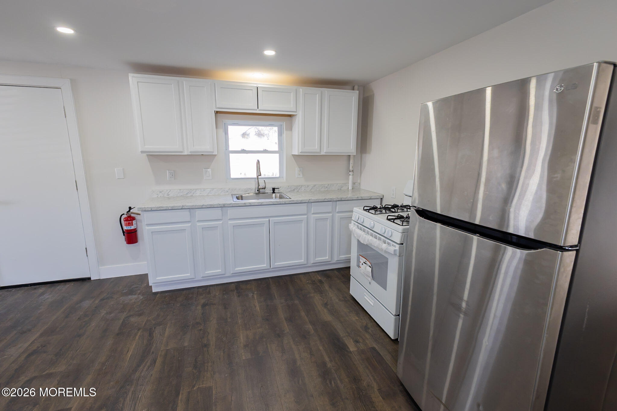 335 Adams Street Eatontown, NJ 07724 - Photo 2 of 10 a kitchen with sink a refrigerator and white cabinets
