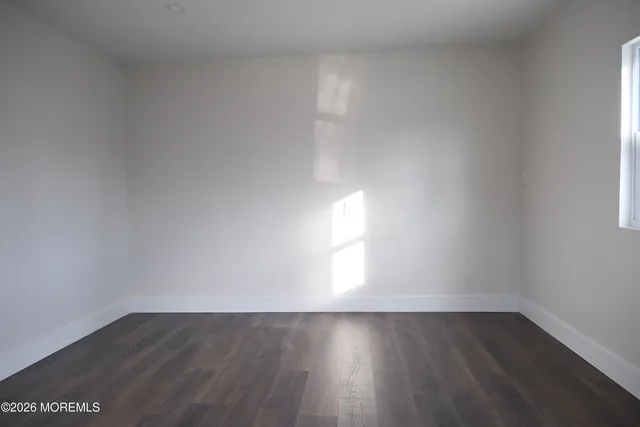 a view of an empty room and wooden floor and window