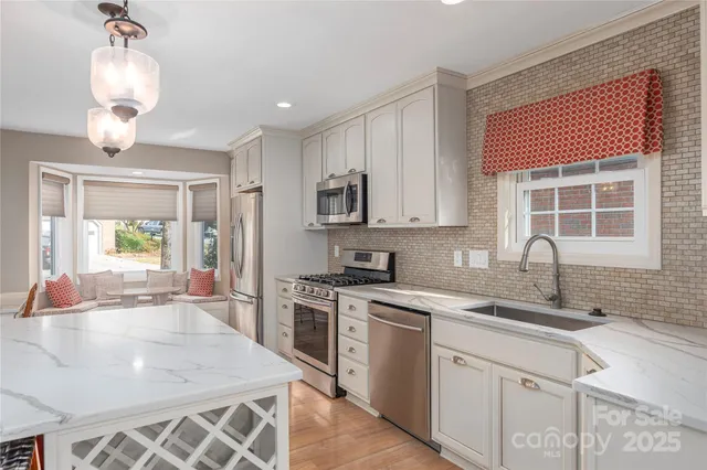 a kitchen with stainless steel appliances granite countertop a sink a stove a refrigerator cabinets and living room view