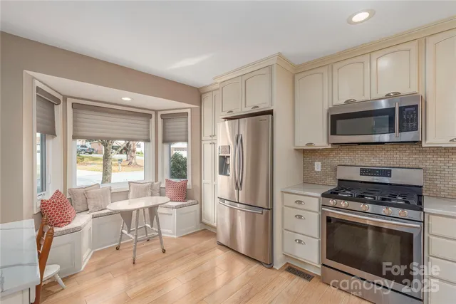 a kitchen with granite countertop a stove a microwave a sink dishwasher a refrigerator with white cabinets and wooden floor