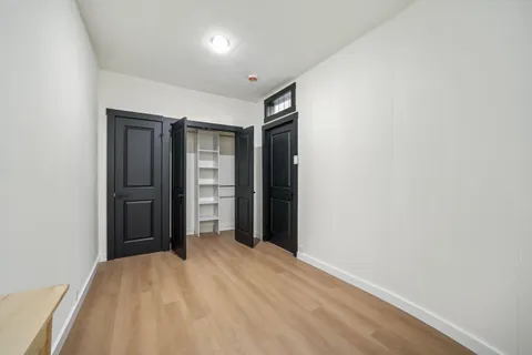 a view of an empty room with closet and wooden floor