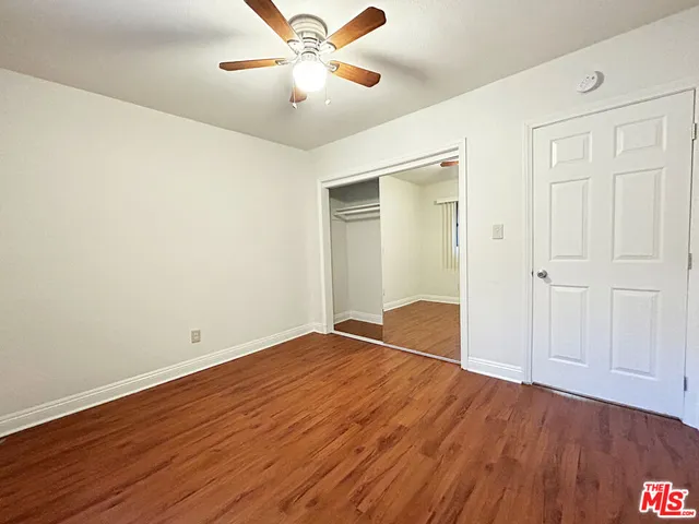 an empty room with wooden floor chandelier fan and windows