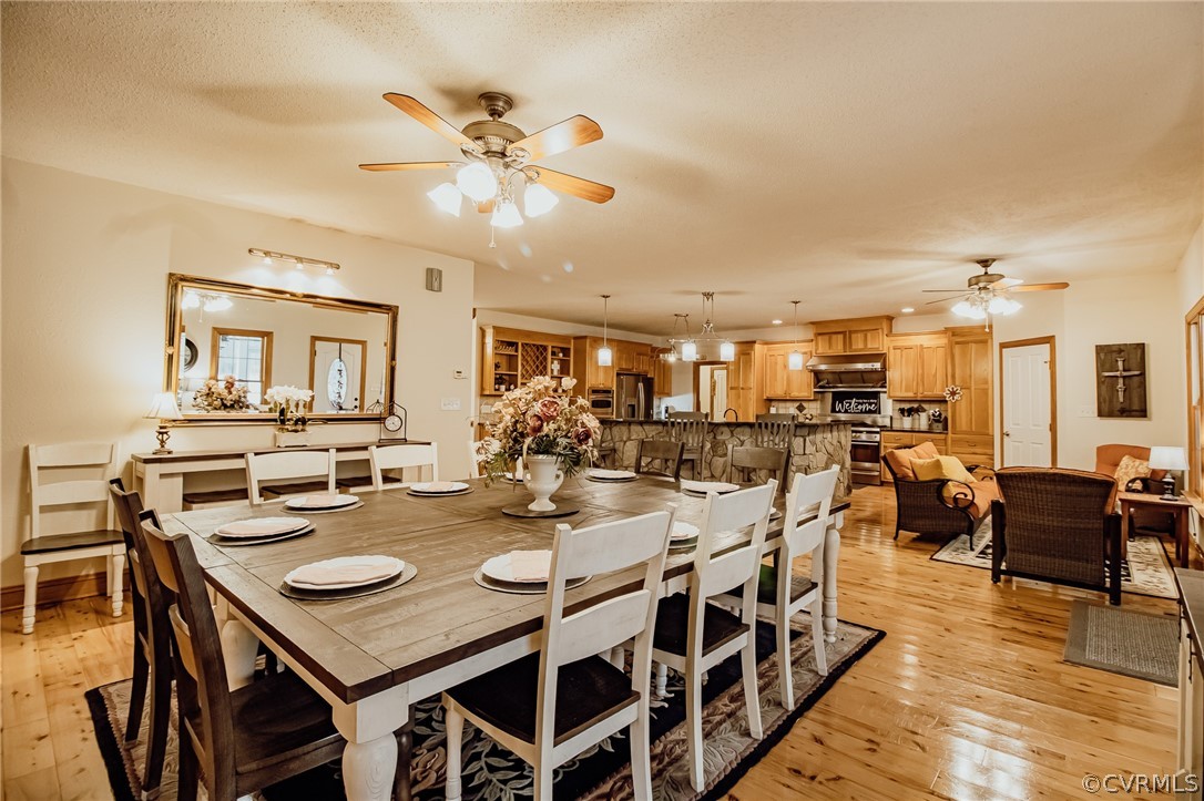 6809 West Quaker Road Disputanta, VA 23842 - Photo 12 of 49 a view of a dining room and livingroom with furniture wooden floor a rug a fireplace and a chandelier