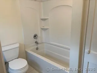 a white toilet sitting next to a bath tub