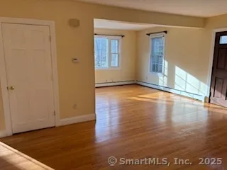 a view of an empty room with window and wooden floor