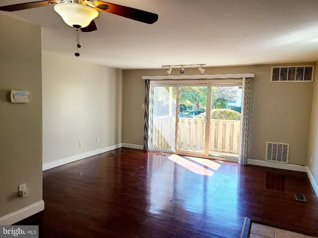 a view of an empty room with a window and wooden floor