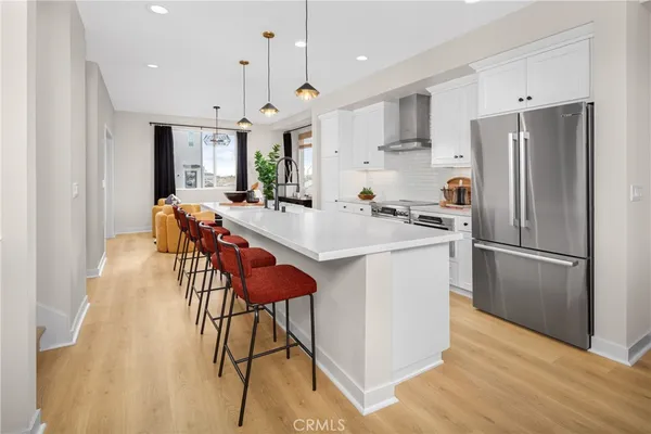 a kitchen with stainless steel appliances granite countertop a refrigerator a sink a stove a dining table and chairs