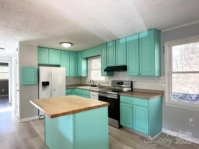a kitchen with granite countertop a sink a stove and refrigerator