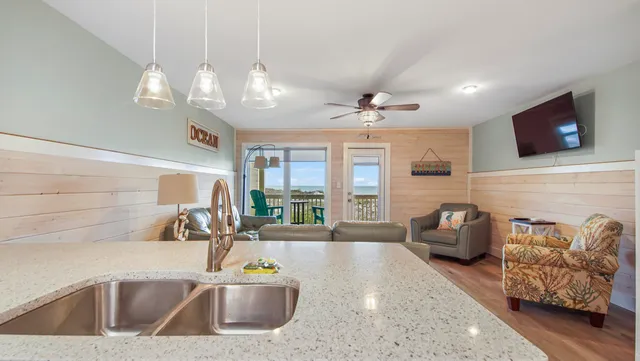 a kitchen with kitchen island granite countertop a sink a counter top space and living room view