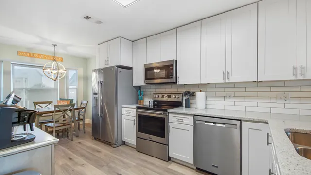 a kitchen with stainless steel appliances granite countertop a stove a sink dishwasher a refrigerator and a microwave oven with wooden floor