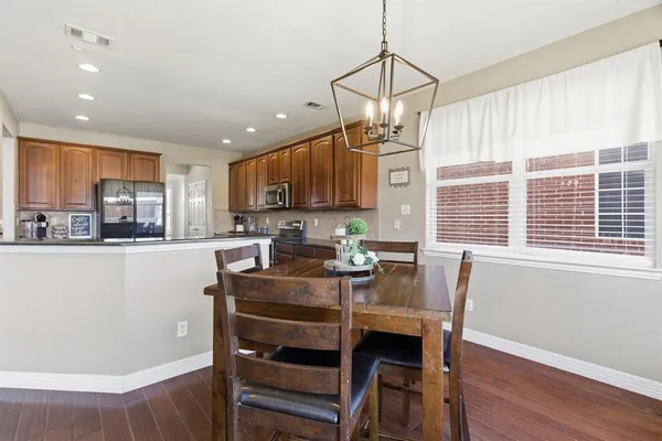 a kitchen with stainless steel appliances granite countertop a refrigerator a sink a stove and white cabinets with wooden floor