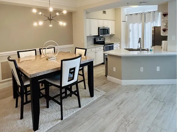 a kitchen with stainless steel appliances kitchen island granite countertop a table chairs microwave and sink