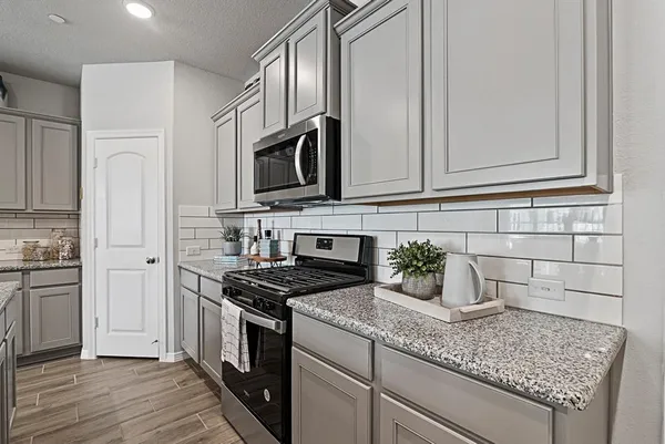a kitchen with stainless steel appliances granite countertop a stove a sink and a microwave