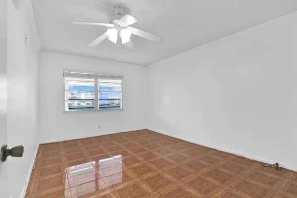 an empty room with windows and ceiling fan