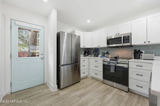a kitchen with white cabinets and stainless steel appliances