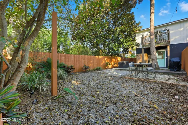 a backyard of a house with large trees and fence