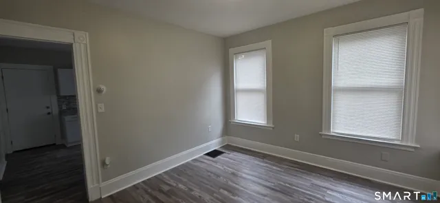 a view of an empty room with wooden floor and a window