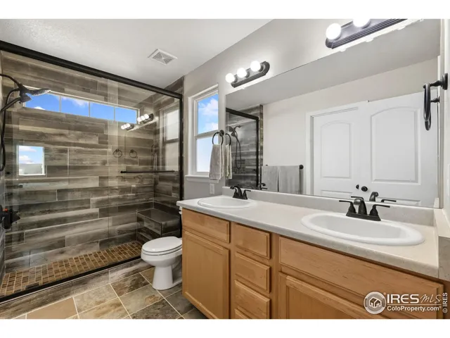 a bathroom with a double vanity sink toilet mirror and shower