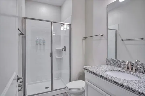 a bathroom with a granite countertop sink toilet and shower