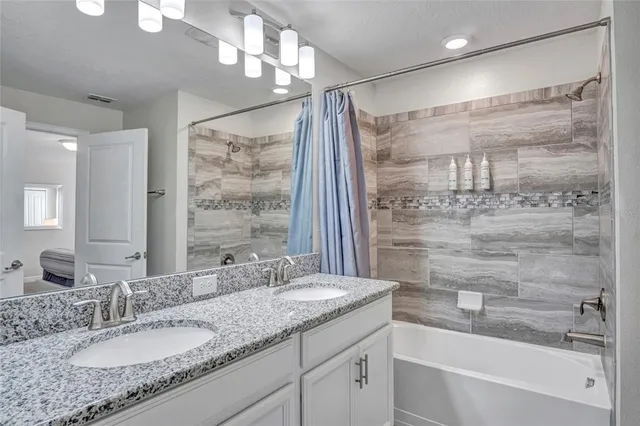 a bathroom with a granite countertop sink a mirror a shower and a bathtub