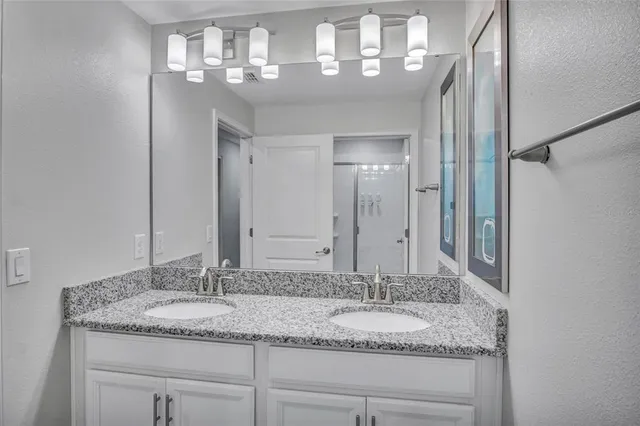 a bathroom with a granite countertop double vanity and a mirror