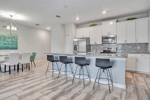 a kitchen with stainless steel appliances kitchen island granite countertop a table chairs and white cabinets