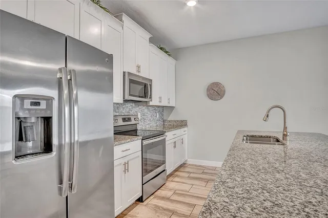 a kitchen with stainless steel appliances granite countertop a refrigerator a stove and a sink