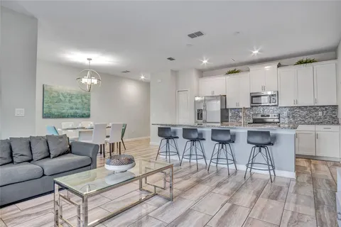 a living room kitchen with a couches and kitchen view with wooden floor