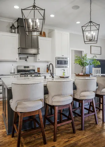 a kitchen with stainless steel appliances a dining table chairs and white cabinets