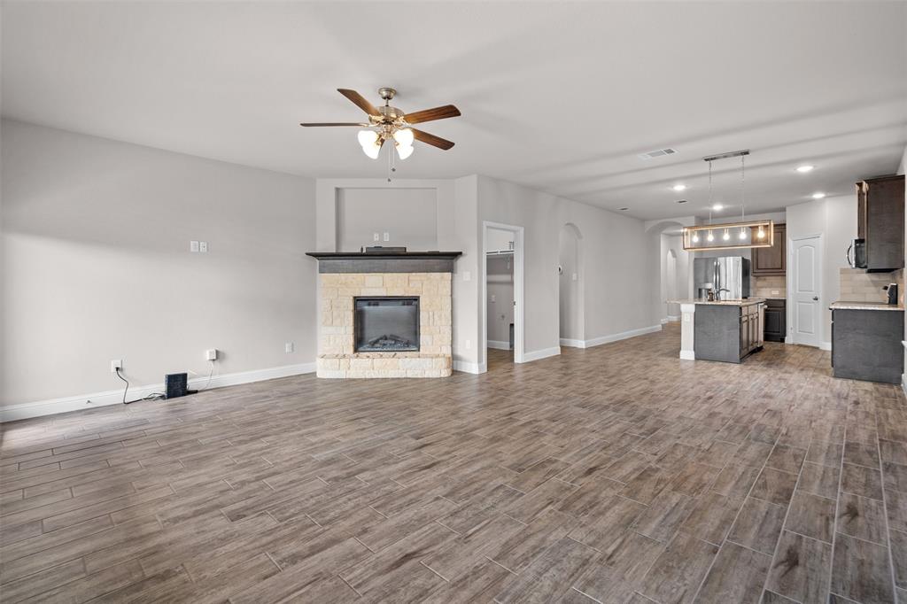 119 Happy Lane Red Oak, TX 75154 - Photo 9 of 37 Spacious living area featuring wood-finish tile flooring, a stone-faced fireplace with a dark mantel, and an open concept layout with recessed lighting