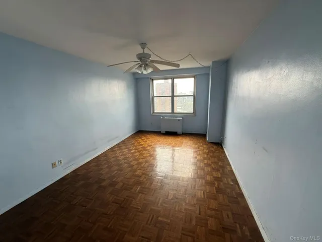 an empty room with a ceiling fan and window