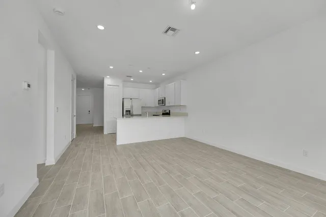 a view of kitchen refrigerator and white cabinets