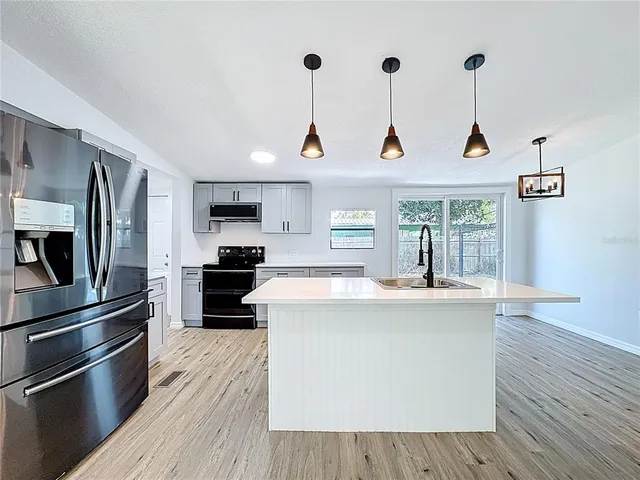 a view of kitchen with sink and refrigerator